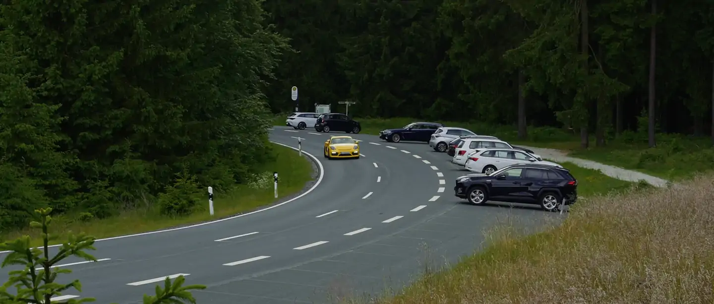 Gelber Porsche Cayman GT4 auf einer Passstraße im Mittelgebirge, aus der Luft gefilmt
